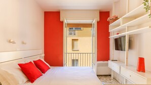 Une chambre d’hôtel avec un lit, une télévision, une petite table et un balcon donnant sur l’immeuble.