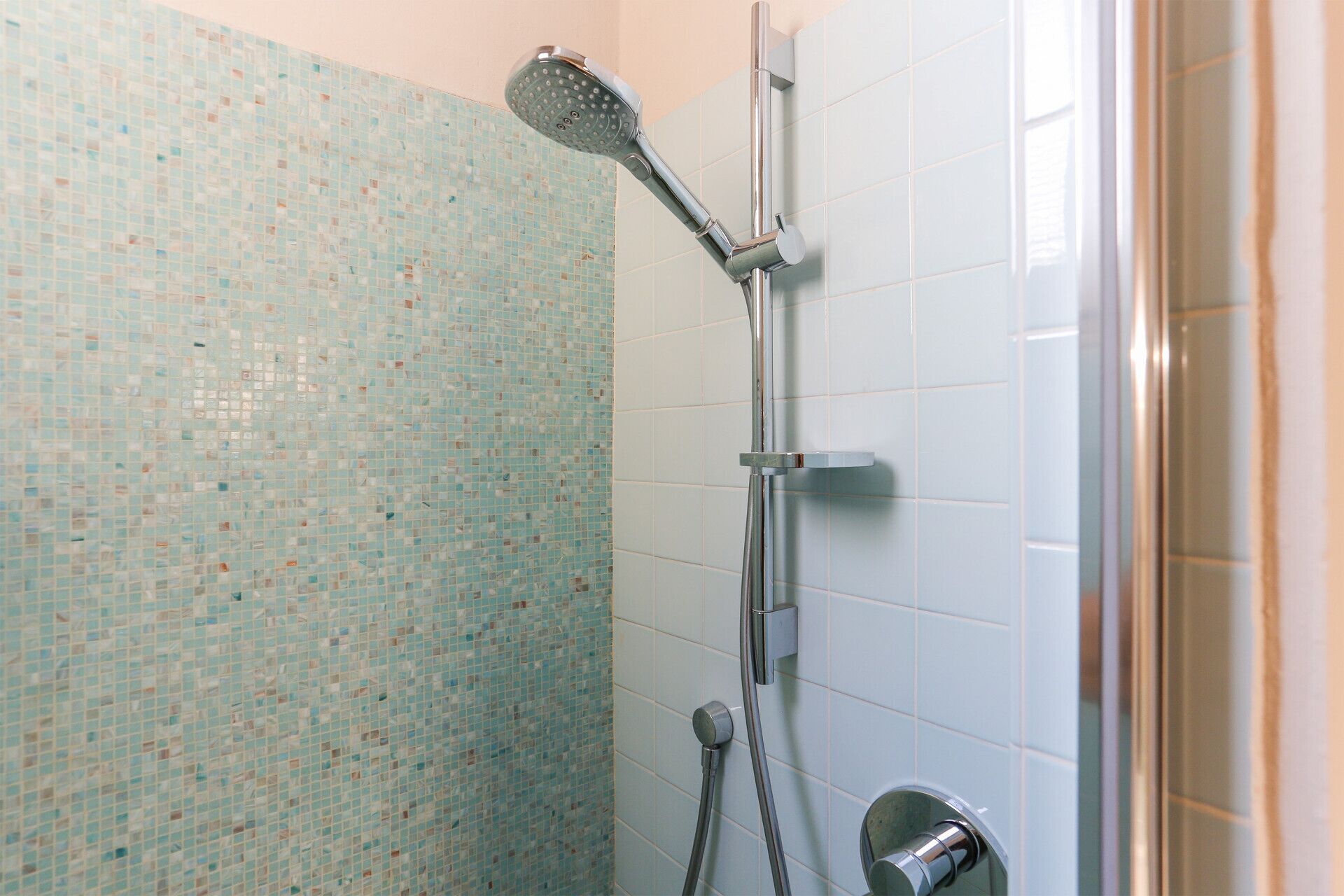 Une douche équipée d’un pommeau de douche à main et de commandes murales.