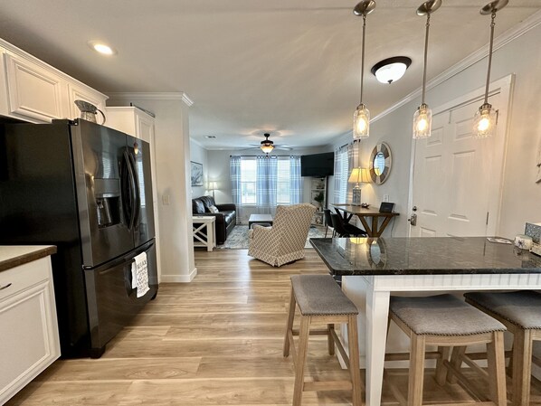 A modern kitchen with a black refrigerator, wooden dining table, and bar stools.