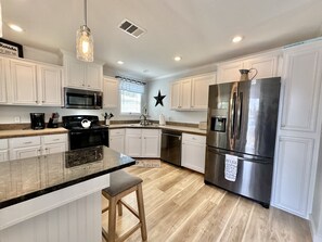 A modern kitchen with white cabinets, stainless steel appliances, and a granite countertop.