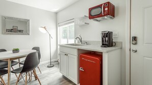 Eine kleine Küche mit einem roten Kühlschrank, einer Mikrowelle, einer Kaffeemaschine und einem Spülbecken.