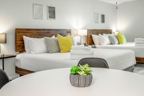 Een hotelkamer met twee bedden, een ronde tafel met een plant in pot en een nachtkastje met een lamp.