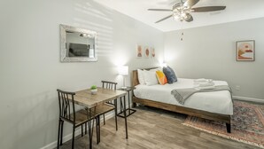 Un dormitorio con cama, mesita de noche, lámpara y ventilador de techo.