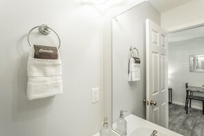 Une salle de bain avec un lavabo blanc, un miroir et un porte-serviettes sur lequel est posée une serviette marron.