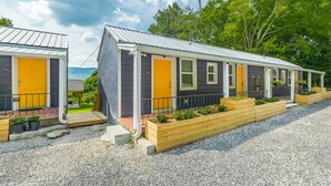 A row of small, dark-colored cabins with yellow doors, each with a small porch and wooden planters.