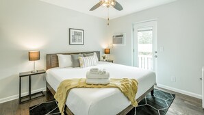 A bedroom with a bed, bedside tables, a ceiling fan, and a door.