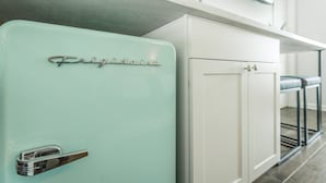 Una cocina de estilo retro con un refrigerador verde menta, armarios blancos y un lavamanos de acero inoxidable.