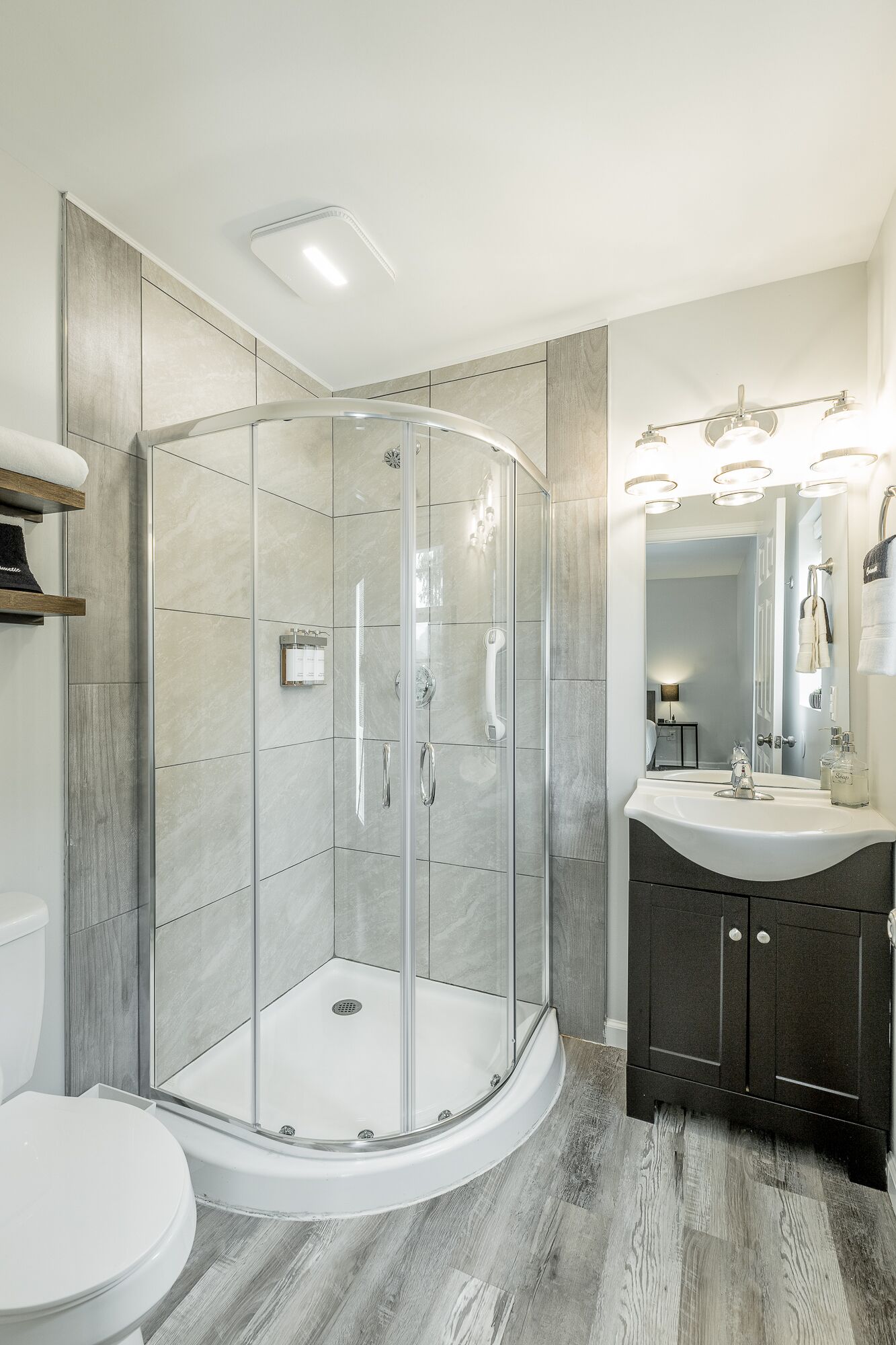 A modern bathroom with a glass-enclosed shower, a vanity with a mirror, and a toilet.