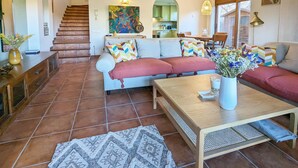 A spacious living area with a sofa set, a coffee table, and a patterned rug. A staircase leads to an upper level. - House in Begur with swimming pool and castle view - 3 bedrooms, sleeps 5 to 6 (Begur)