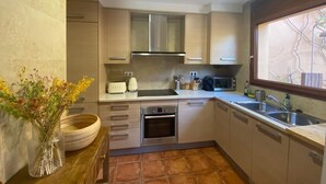 A compact kitchen with wooden cabinets, a built-in oven, a microwave, and a sink. - House in Begur with swimming pool and castle view - 3 bedrooms, sleeps 5 to 6 (Begur)