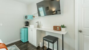 A compact kitchenette with a microwave, coffee maker, and a small refrigerator. A flat-screen TV is mounted on the wall above the counter. - 10: The Jacobsen Room - A PMI Scenic City Vacation Rental (Chattanooga)