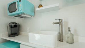 A kitchen with a white sink, a stainless steel faucet, a Keurig coffee maker, and a teal-colored microwave. - 10: The Jacobsen Room - A PMI Scenic City Vacation Rental (Chattanooga)