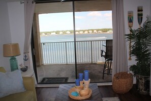 A room with a view of the sea, a sofa, a table with decorative items, and a potted plant.