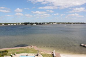 A waterfront property with a swimming pool, lounge chairs, and a dock extending into the water. - Compass Point 506, a beautiful lagoon-front 1BR. Great views, decor & amenities (Gulf Shores)