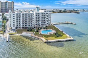 A high-rise hotel with multiple balconies, a swimming pool, and a waterfront view.