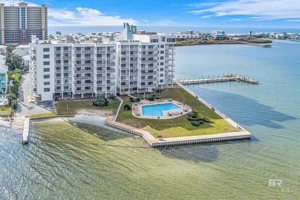 A high-rise hotel with multiple balconies, a swimming pool, and a waterfront view.