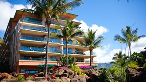 A multi-story hotel with balconies, palm trees, and a rocky garden with a waterfall.