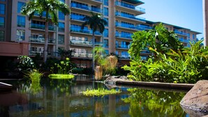 A hotel with a large pool surrounded by lush greenery and palm trees.