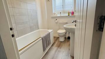 Une salle de bain moderne équipée d’une baignoire, de toilettes et d’un lavabo.