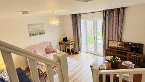 A spacious living area with a staircase, a dining table set for two, and a view of the outdoors.