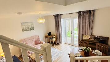 A spacious living area with a staircase, a dining table set for two, and a view of the outdoors.