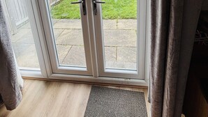 A sliding glass door leading to a backyard with a grassy area and a brick building in the background.