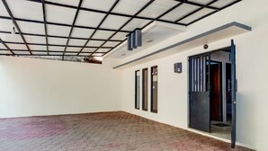 Een ruimte met tegels op de vloer, een plafond met metalen frame en een deur naar een andere kamer.