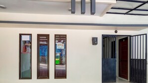 Een moderne gevel met drie hoge ramen en een zwart metalen hek.