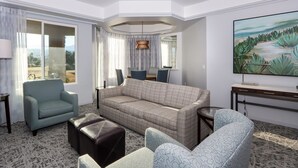 Ett modernt hotellrum med en stor soffa, en liten fåtölj, ett soffbord och en tavla på väggen.
