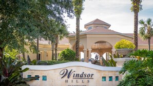 A sign for Windsor Hills Clubhouse with a covered entrance and palm trees. - The Wish House, just miles from Disney World (Four Corners)