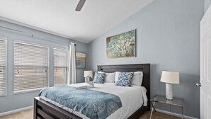 A bedroom with a bed, two bedside lamps, a nightstand, a painting on the wall, and a ceiling fan. - The Wish House, just miles from Disney World (Four Corners)