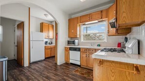 A compact kitchen with wooden cabinets, a white refrigerator, a microwave, a dishwasher, and a gas stove. - Breathtaking View 2BD/1BTH Unit in Central SD (San Diego)
