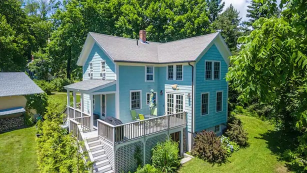 A two-story house with a porch, a small deck, and a well-maintained lawn. - Cottage in Downtown Mystic (Mystic)
