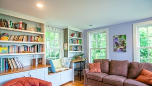A cozy living room with a bookshelf, a sofa, and a chair. - Cottage in Downtown Mystic (Mystic)