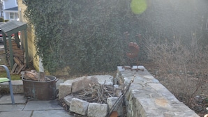 A stone wall with a fire pit and a metal sculpture. - Cottage in Downtown Mystic (Mystic)