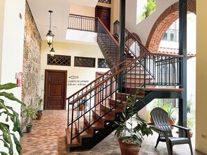 Ein mehrgeschossiges Interieur mit Treppe, Blumentöpfen und Fliesenboden.