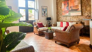 A spacious living room with wicker furniture, a stone wall, and a large window.