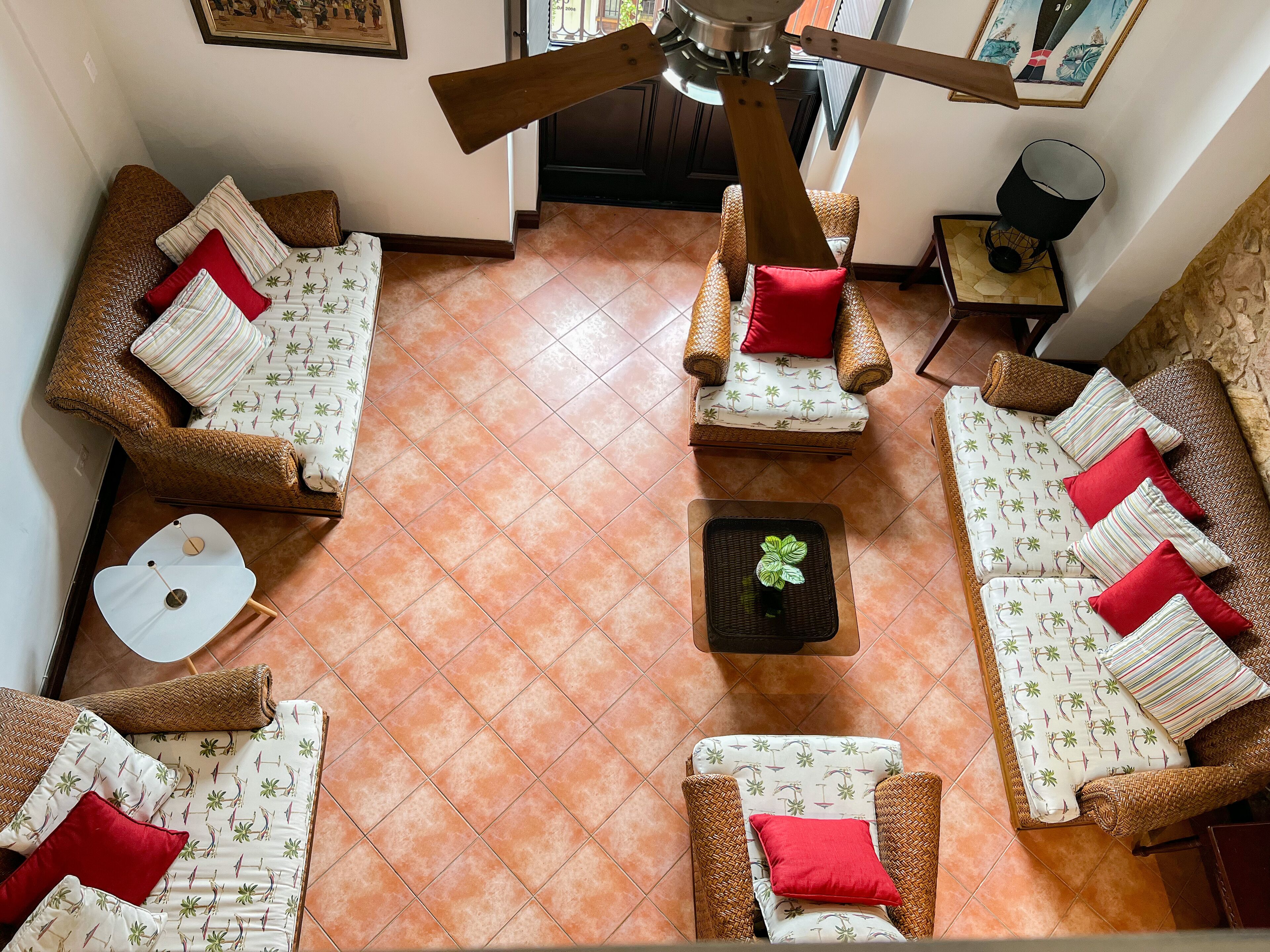Ein Zimmer mit Deckenventilator, Korbmöbeln und Fliesenboden.