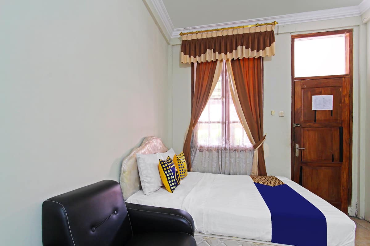 Une chambre à coucher avec un lit, une chaise et une fenêtre avec des rideaux.