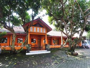 A traditional building with a tiled roof, surrounded by trees and a cobblestone pathway.