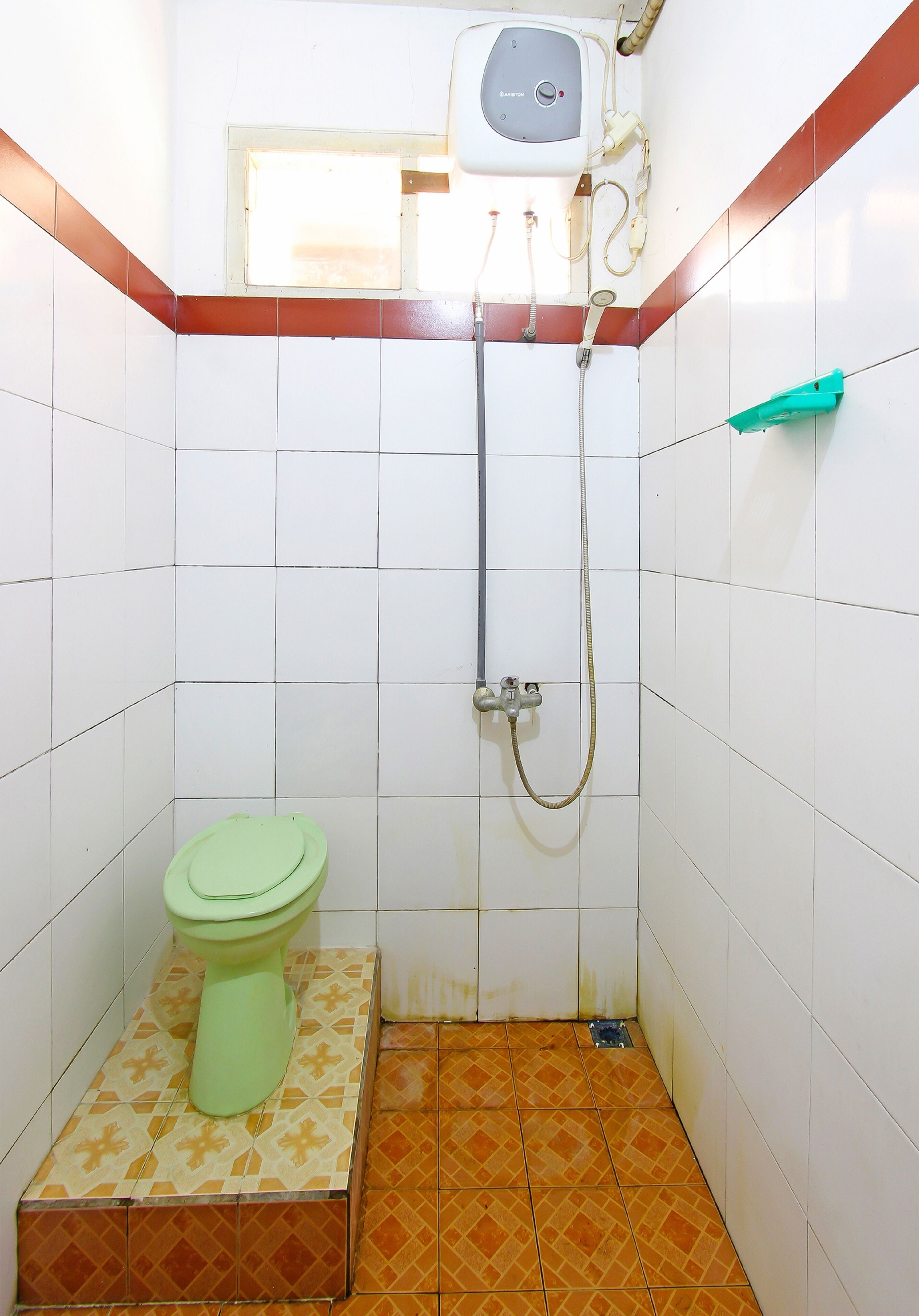 Une petite salle de bain avec des toilettes, une douche et une fenêtre.