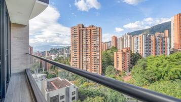 Un edificio de gran altura con múltiples balcones, rodeado de otros edificios altos y zonas verdes.