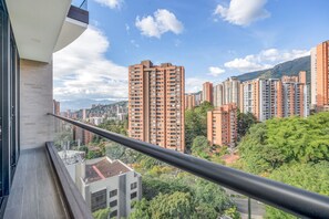 Un immeuble de grande hauteur doté de nombreux balcons, entouré d’autres immeubles de grande hauteur et de verdure.
