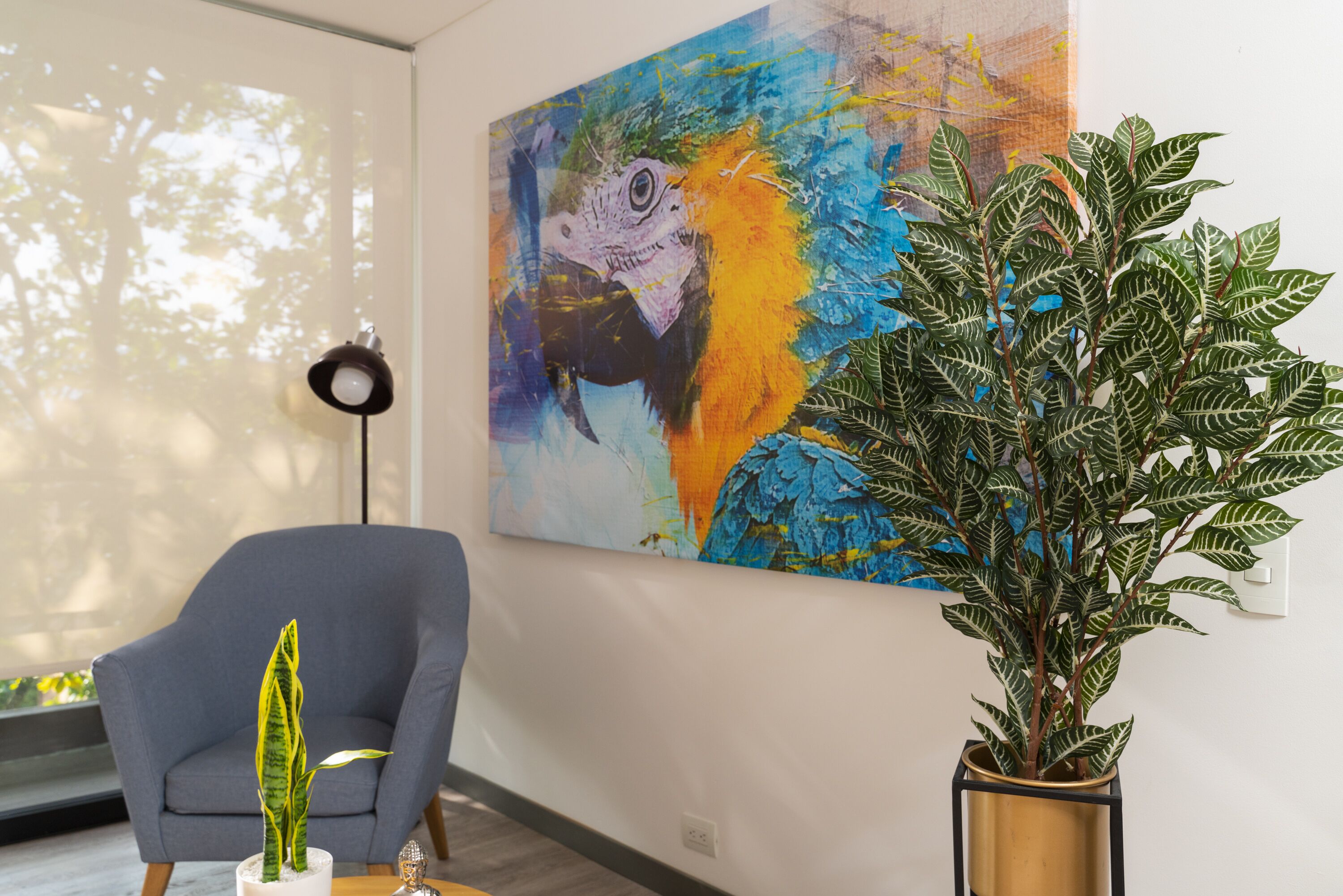 A room with a large abstract painting, a potted plant, a modern armchair, and a floor lamp.