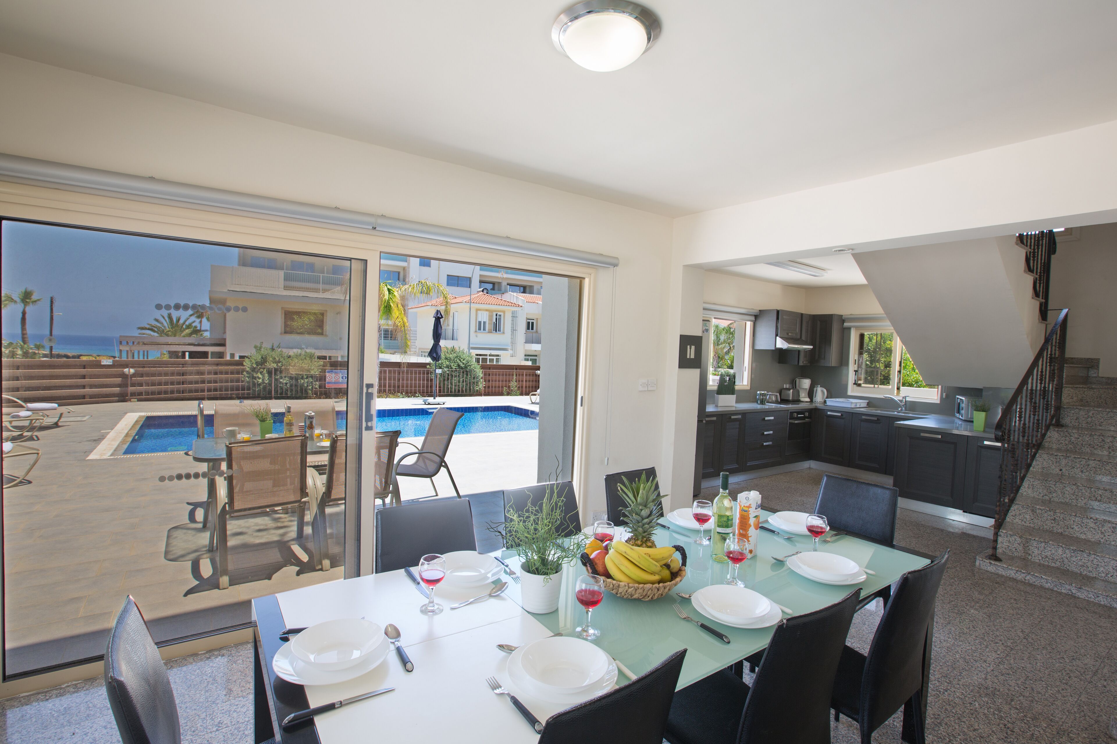 A dining area with a view of a swimming pool and a kitchen.