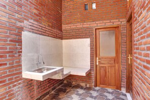 A bathroom with a built-in sink, a wooden door, and a tiled floor. - SPOT ON 90882 Sari Homestay Near Garuda Wisnu Kencana (Ungasan)