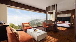 A modern hotel room with a large window, a sofa, a desk, a bed, and a ceiling fan. - Fortune Resort Kalimpong - Member ITC Hotels' Group (Kalimpong)