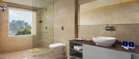 A modern bathroom with a large window, a walk-in shower, a white sink, and a mirror.