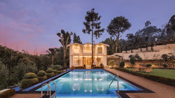 A swimming pool with a wooden deck, surrounded by well-maintained landscaping and a large house with multiple windows and a balcony. - Fortune Resort Kalimpong - Member ITC Hotels' Group (Kalimpong)