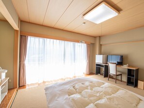 A hotel room with a bed, a desk with a computer and TV, and a large window with curtains. - Chateraise Lodge Kasugai (Fuefuki)